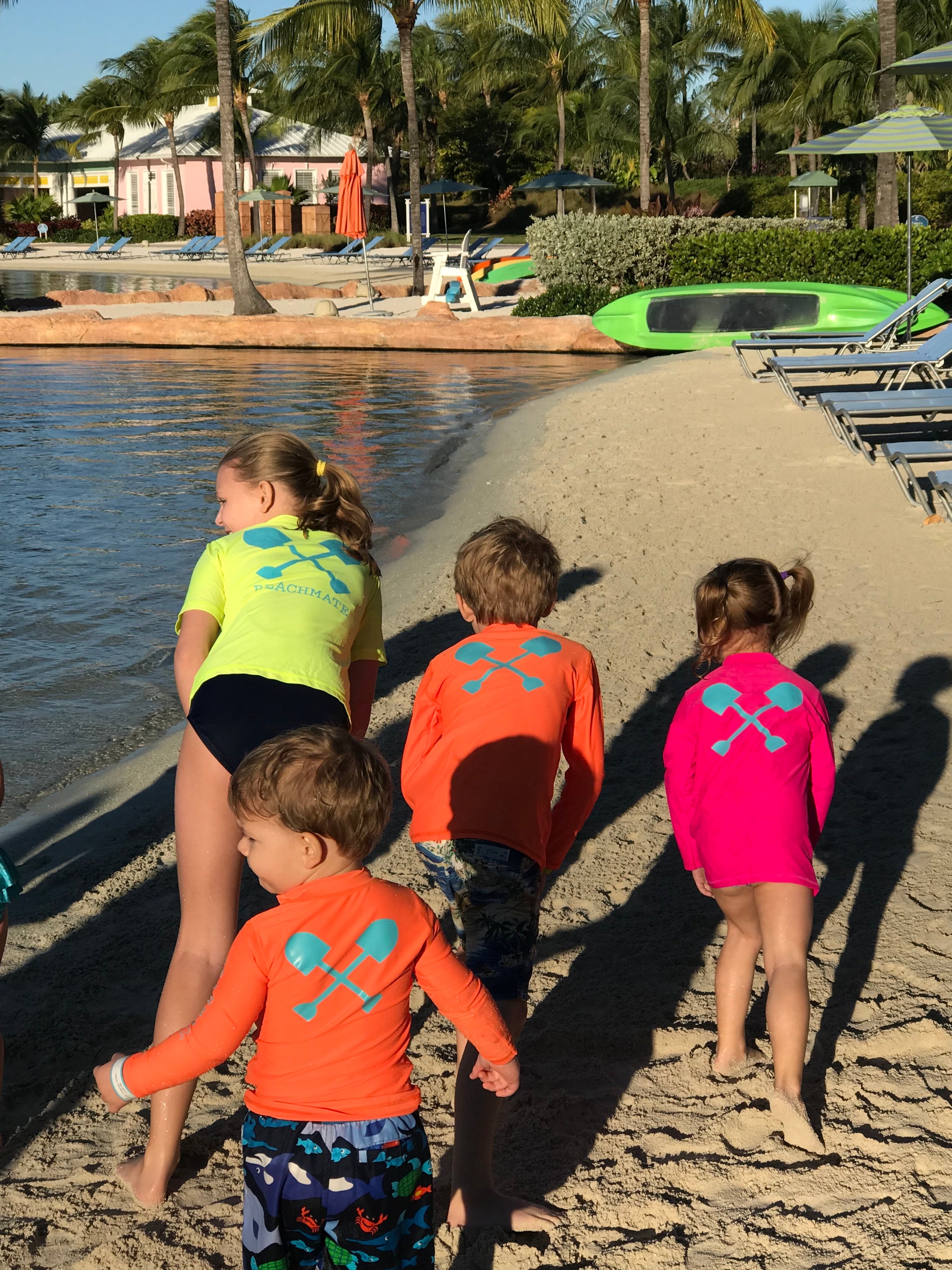 Kids on the beach wearing bright Beachmate long‑sleeve UPF 50 rash guards