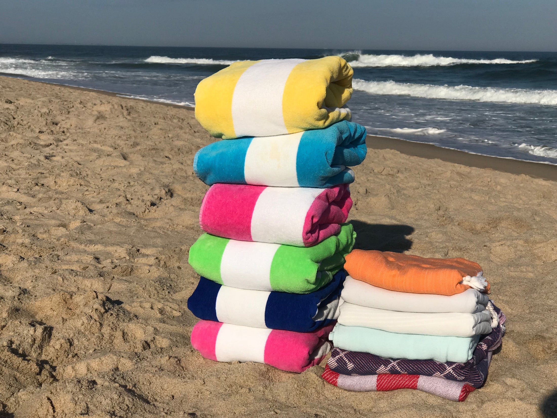 Lifestyle photo of mint Turkish, yellow,light pink towel at the beach