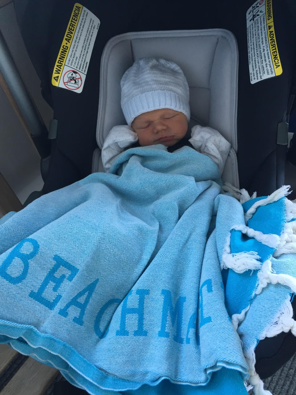 Turquoise Turkish towel used as a light cover with a baby seated, soft cotton fabric