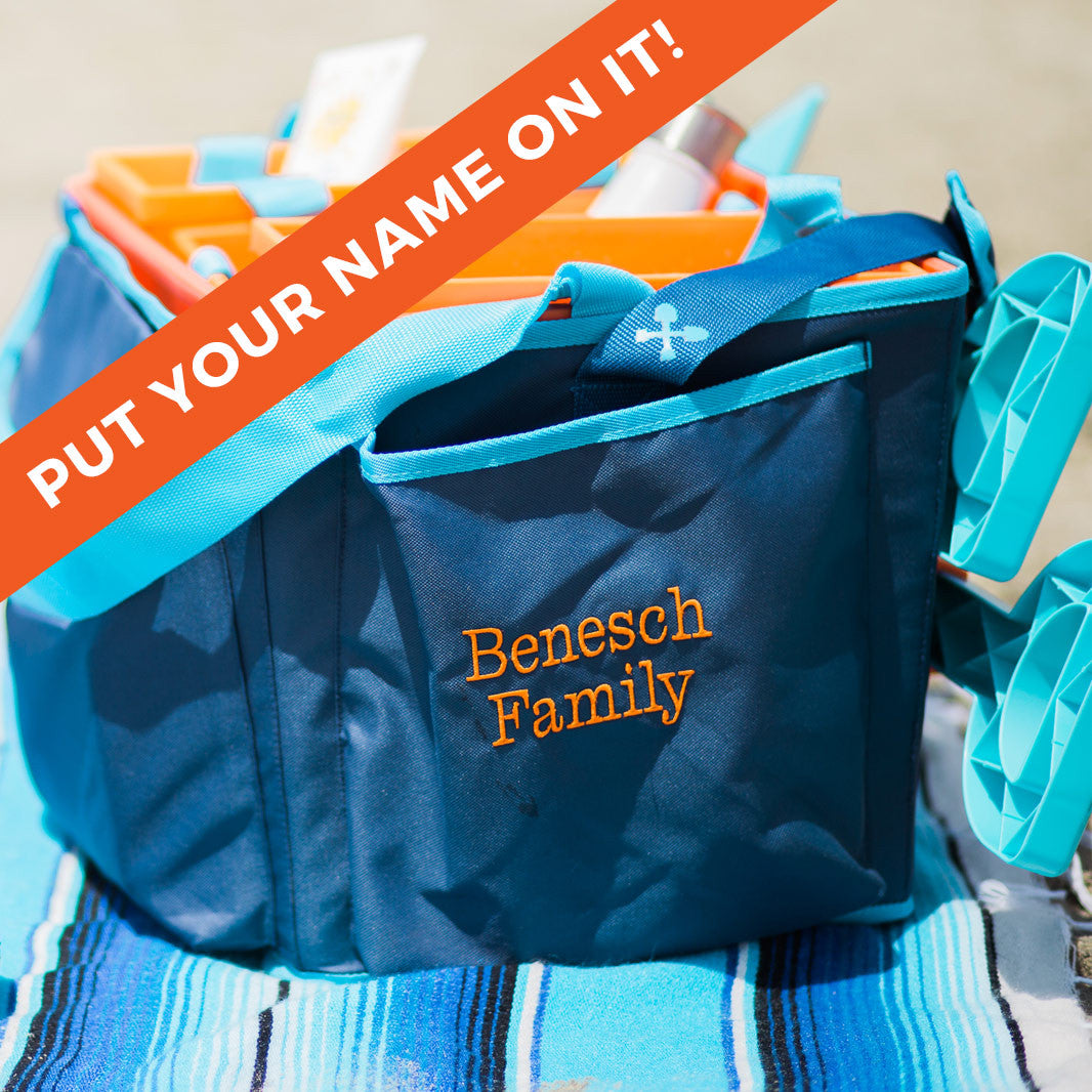 A blue and orange Beachmate tote bag with 'Benesch Family' customized in orange embroidery on the side, presented at a beach setting.